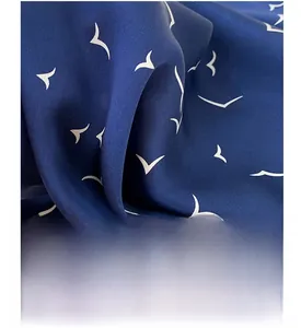 Detailed close-up of dark blue silk scarf with white seagull print and satin finish texture