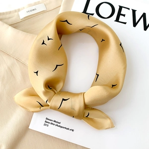 Silk square scarf with seagull print on gold satin fabric over a beige shirt