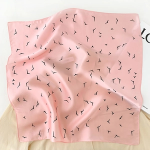 Detailed shot of pink silk scarf with black bird prints and soft satin texture