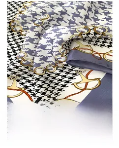 Detailed close-up of rolled hem edges on a silk scarf with houndstooth and chain patterns