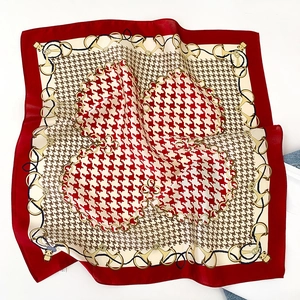Detail of red silk scarf with houndstooth pattern, golden chains, and horsebit motifs