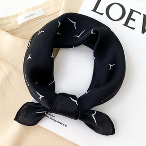 Silk neck scarf with white seagull print on black fabric over a beige shirt