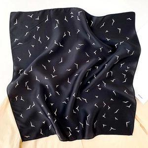 Macro view of black 100% mulberry silk square scarf featuring white seagull patterns