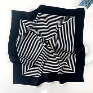 Detail of square silk scarf with black and white geometric patterns and smooth texture