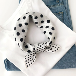 Close-up of knotted mulberry silk scarf featuring classic black polka dots on white silk