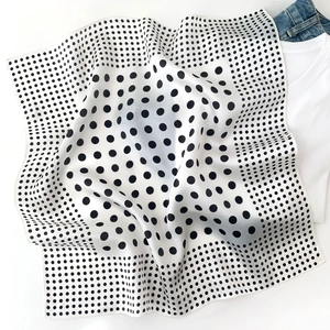 Detail of silk scarf with black and white polka dot pattern showing smooth satin texture