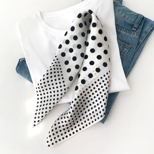 Detailed view of a black and white polka dot silk scarf styled with casual clothing