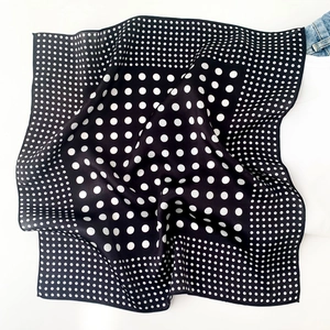 Detail of silk scarf with black and white polka dot pattern and satin texture