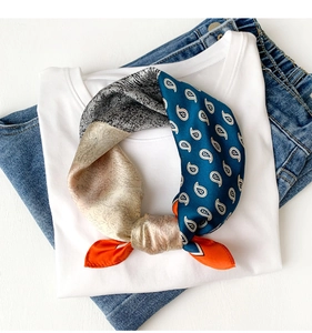 Detail of multi-color paisley silk scarf styled on white t-shirt and blue jeans