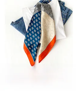 Detailed close-up of silk square scarf with paisley print and orange stitched edges