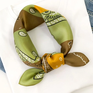 Detail of silk paisley scarf with green and brown color blocking on a white t-shirt