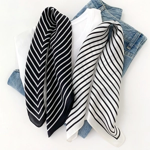 Detail of black and white striped silk scarves paired with a white T-shirt and blue jeans