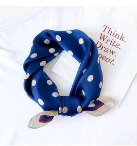 Detail of silk square scarf showing navy blue polka dot pattern and soft texture