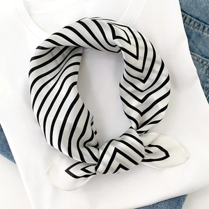 Detail of silk scarf with black and white V-shaped stripes tied on denim and t-shirt