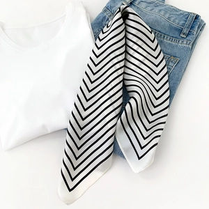 Flat lay of black and white zigzag stripe silk scarf on white t-shirt and blue denim jeans