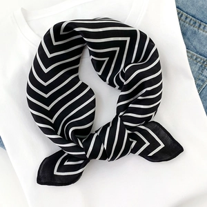 Detail of silk scarf with black and white stripes on white shirt and denim base