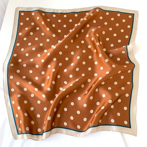 Detail of silk square scarf featuring retro brown polka dots and a contrast border edge