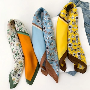 Detail of colorful silk neck scarves with premium hemmed edges on denim background