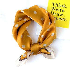 Detail of silk square scarf in ginger yellow with white polka dots and dark border