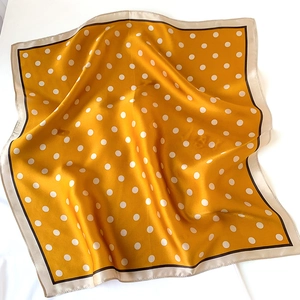 Detailed view of yellow silk square scarf with white polka dots and elegant borders
