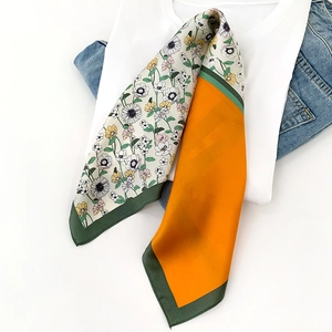 Flat lay detail of a floral silk scarf with daisy patterns and orange color block detail