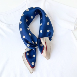 Detail of silk square scarf with white polka dots on royal blue fabric and contrast border
