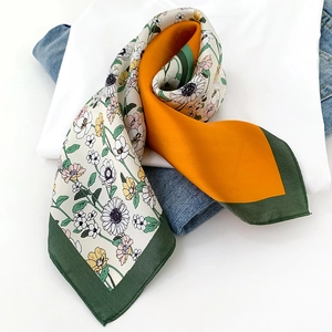 Close-up of silk scarf with daisy prints and color-block edges on a white t-shirt