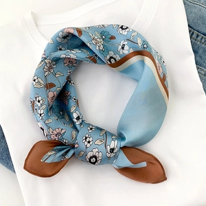 Detail of blue floral silk scarf with pink flowers and contrasting brown edges