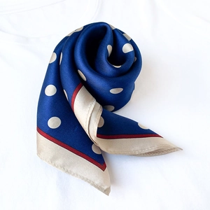 Detail of silk square scarf featuring navy blue polka dots and red edge accents