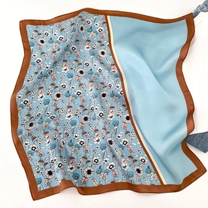 Detail shot of silk scarf with blue daisy print and brown satin border on casual clothing