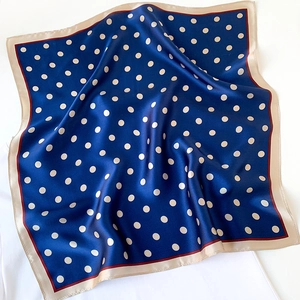 Detail of blue polka dot silk scarf featuring smooth texture and contrasting red edge