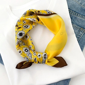 Detail of yellow silk scarf with floral print tied in a bow on a white t-shirt