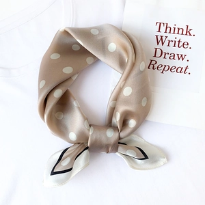 Detail of silk scarf with white polka dots on champagne gold fabric over white tee