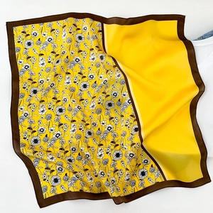 Detail of color-block silk scarf featuring yellow panel and floral print edge