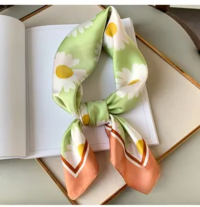 Detailed view of daisy print silk scarf with green and orange pastel color blocks