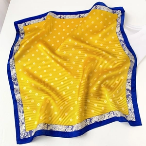 Detailed view of yellow and navy silk scarf with polka dots and white paisley patterns