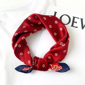 Close-up of silk scarf with red sunburst and navy paisley patterns on white shirt