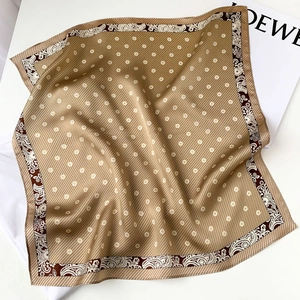 Detail of silk scarf showing brown paisley border and delicate floral pattern on satin