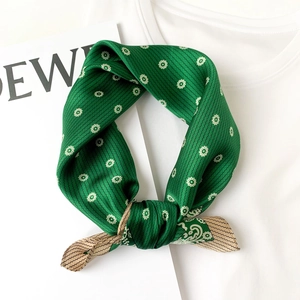 Detailed shot of green silk scarf featuring white daisy floral and wavy stripe patterns