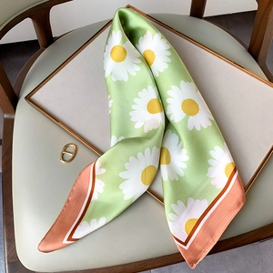 Detail of silk daisy scarf with green floral pattern and contrast border finish