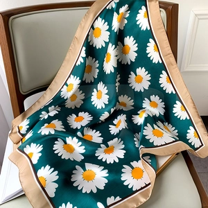 Close-up of silk square scarf featuring white daisy prints on dark green fabric