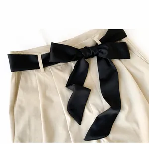 Detail view of khaki trousers featuring a stylish black satin bow waist tie and neat seams