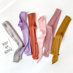 Close-up of narrow satin scarves in six pastel colors arranged on a white background