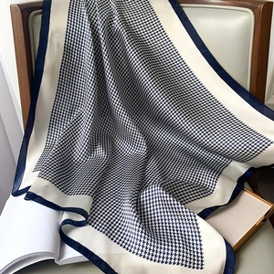 Detail of navy blue houndstooth silk scarf elegantly draped on a classic armchair