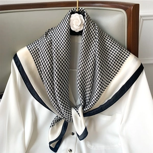 Detailed view of black and white houndstooth silk scarf tied on a white chiffon shirt