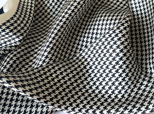 Close-up of silk-textured houndstooth scarf fabric with elegant folds and glossy finish