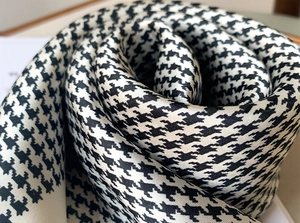 Macro view of satin silk scarf featuring classic black and white houndstooth pattern detail