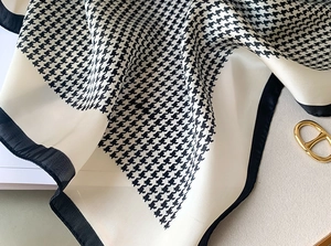 Detailed macro view of the houndstooth silk scarf texture with black border edges
