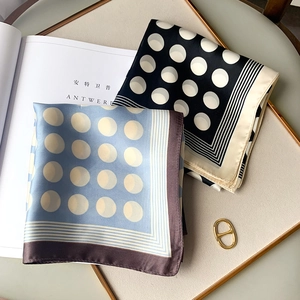 Polka dot silk neck scarf in light blue and black shown on a decorative tray