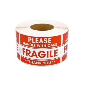 Close-up of a roll of red fragile warning stickers with white handle with care text